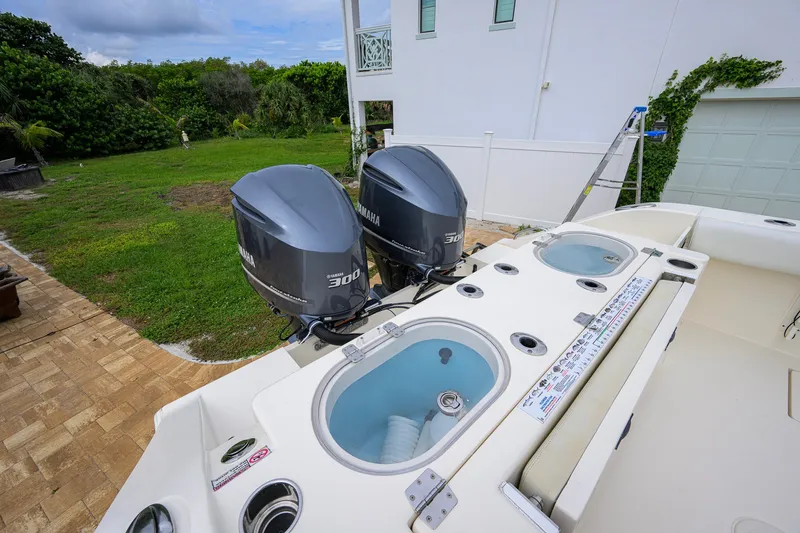 Slide: The Image of 2019 Cobia 301 Center Console boat with dual Yamaha 300 engines, docked near a house. - 17