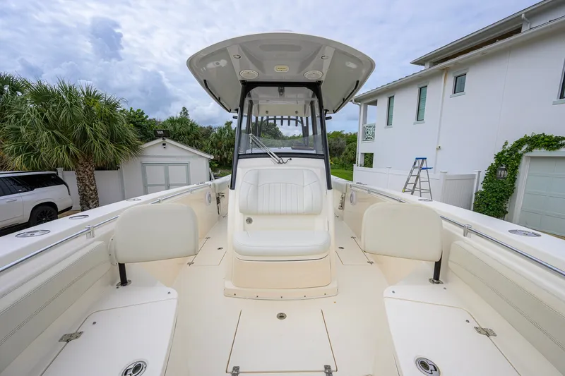 Slide: The Image of 2019 Cobia 301 Center Console boat with spacious seating, parked near a white house. - 52