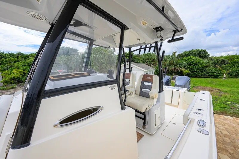 Slide: The Image of 2019 Cobia 301 Center Console boat with dual seats and sleek design, docked outdoors. - 33