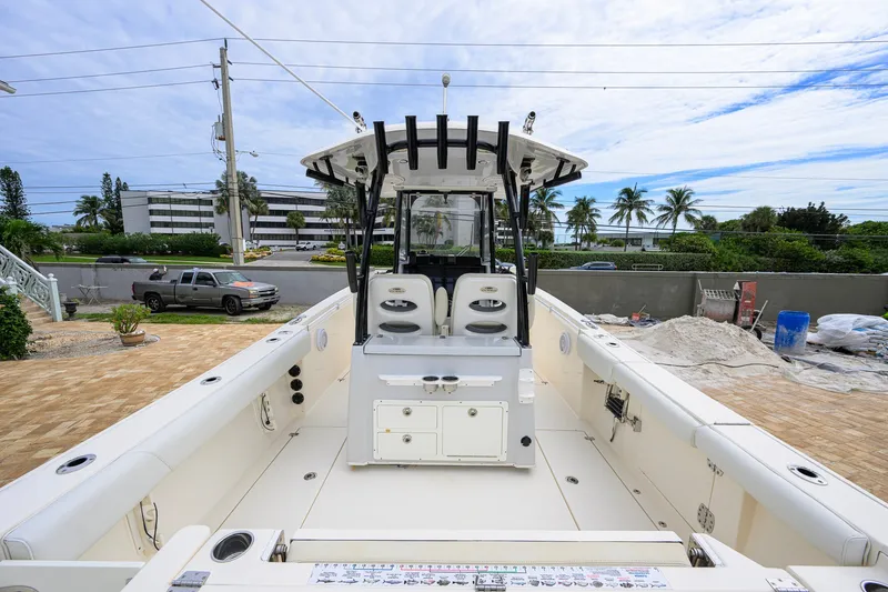 Slide: The Image of 2019 Cobia 301 Center Console boat with spacious deck and dual seating, parked outdoors. - 4