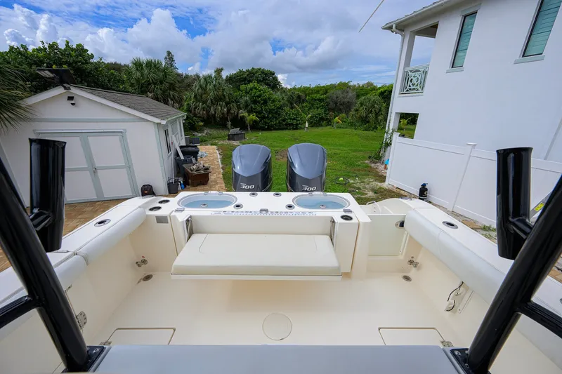 Slide: The Image of 2019 Cobia 301 Center Console boat with twin engines, parked near a house and garage. - 28