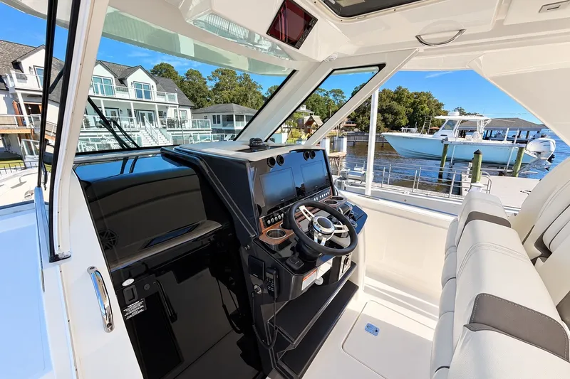 Slide: The Image of 2023 Tiara Yachts 34 LS helm with modern controls, docked near waterfront homes. - 15