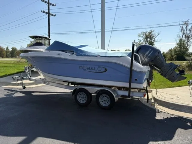 Slide: The Image of A 2023 Robalo R207 Dual Console boat on a trailer, with a blue cover and outboard motor. - 5