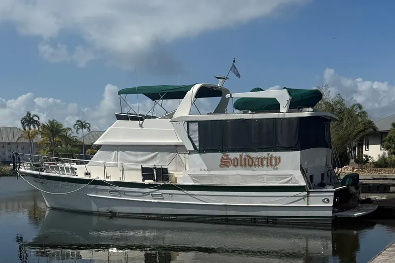 The Image of 1989 Jefferson Marquessa 52 Extended Deckhouse yacht named "Solidarity" docked by palm trees. - 0