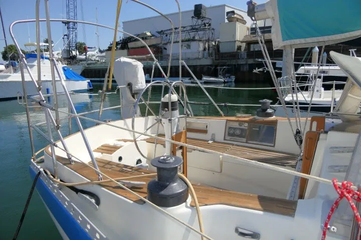 Slide: The Image of 1984 Wauqueize Hood 38 MK II sailboat docked, featuring a spacious cockpit and marina backdrop. - 30