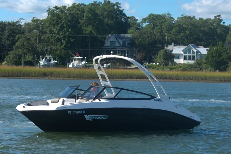 The Image of 2025 Yamaha Boats AR190 on a serene lake with houses in the background. - 0