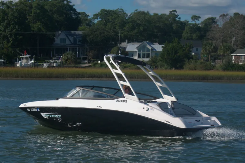Slide: The Image of 2025 Yamaha Boats AR190 cruising on a scenic waterway with lush greenery. - 2