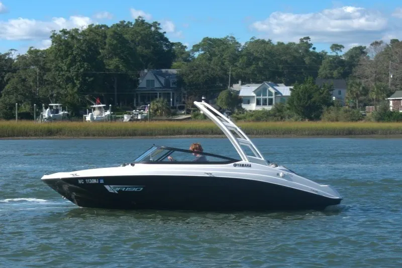 Slide: The Image of 2025 Yamaha Boats AR190 cruising on a scenic river with lush greenery. - 1