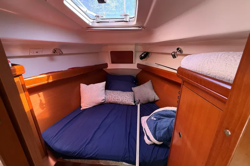 Slide: The Image of Cozy cabin interior of 2006 Beneteau Oceanis 343 sailboat with blue bedding and wooden finish. - 22
