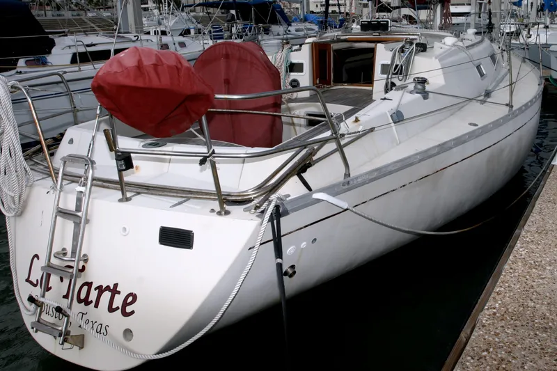 Slide: The Image of 1983 Beneteau Idylle 11.50 sailboat docked, featuring a sleek white hull and deck. - 14