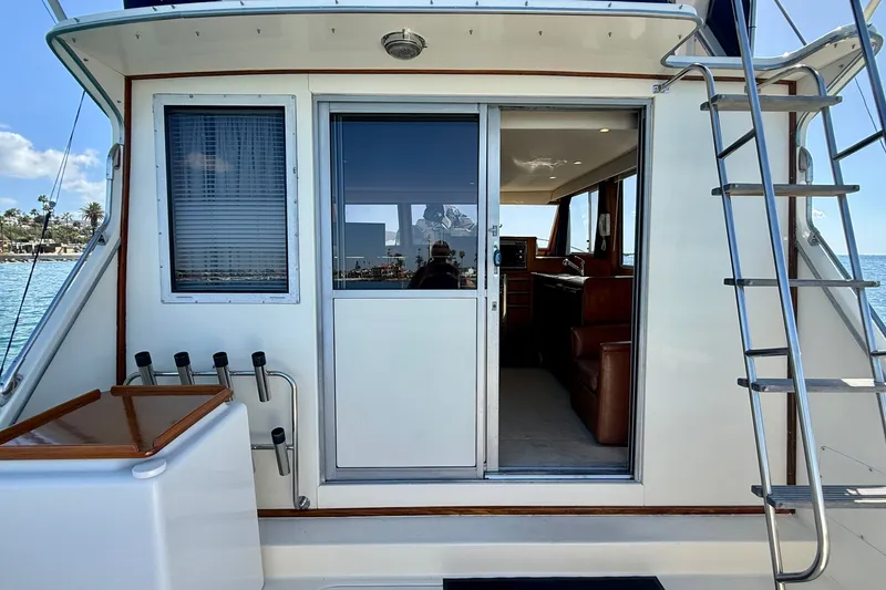 Slide: The Image of 1985 Chris-Craft 382 Commander yacht with open cabin door and ladder, docked by the sea. - 47