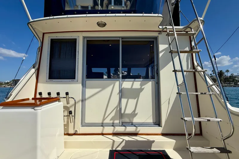 Slide: The Image of 1985 Chris-Craft 382 Commander yacht with ladder and sliding door, docked under clear blue sky. - 46