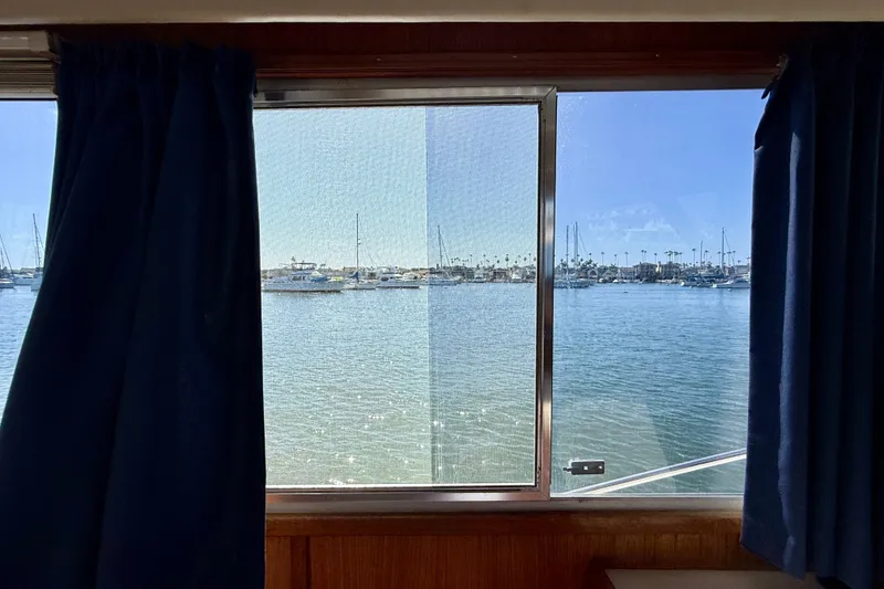Slide: The Image of View from 1985 Chris-Craft 382 Commander boat window overlooking marina with blue curtains. - 15