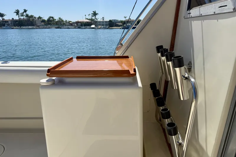 Slide: The Image of 1985 Chris-Craft 382 Commander boat deck with rod holders and wooden tray, overlooking water. - 78