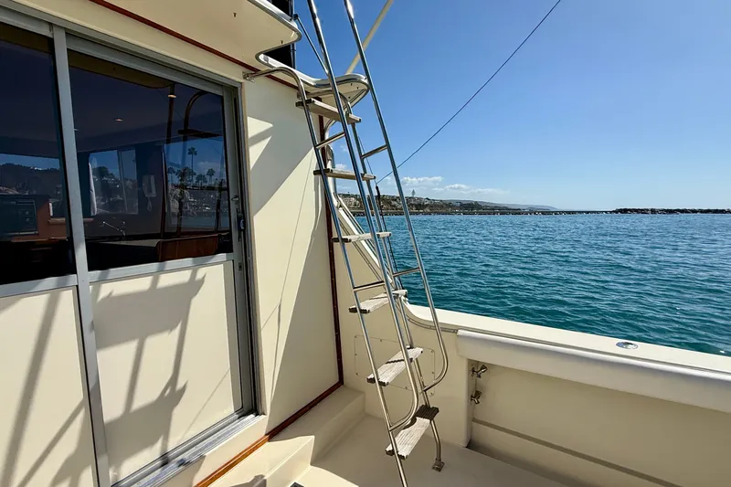 Slide: The Image of 1985 Chris-Craft 382 Commander yacht with ladder, docked by the ocean under clear skies. - 49