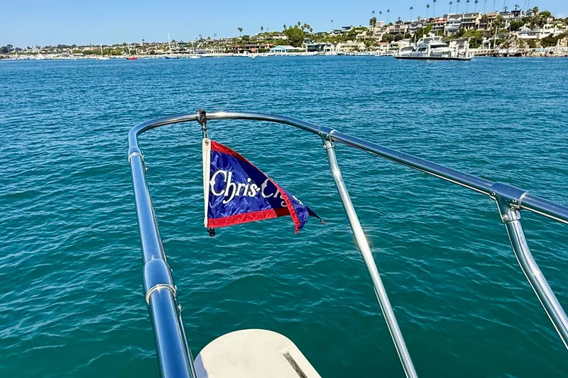 Slide: The Image of 1985 Chris-Craft 382 Commander boat with flag, overlooking coastal waters and shoreline. - 73