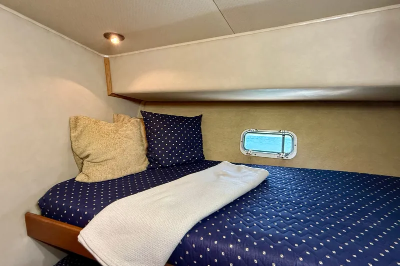 Slide: The Image of Cozy cabin interior of 1985 Chris-Craft 382 Commander with blue bedding and porthole window. - 35
