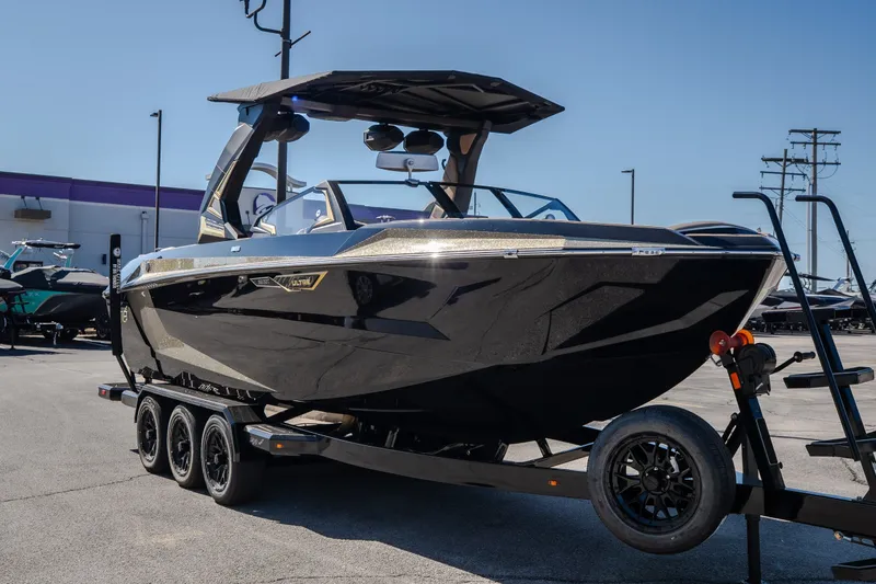 Slide: The Image of 2027 Tigé Ultré 25ZX boat on trailer, sleek black design, parked outdoors. - 21