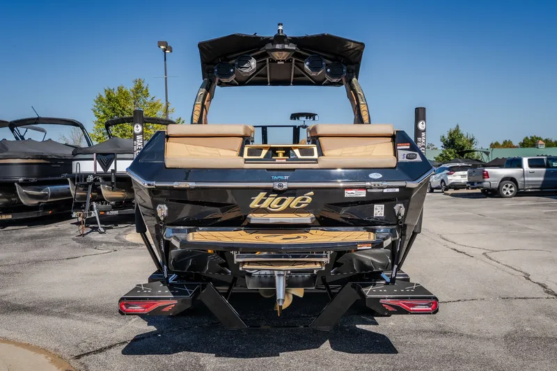 Slide: The Image of 2027 Tigé Ultré 25ZX boat, rear view, in a parking lot under clear blue sky. - 28