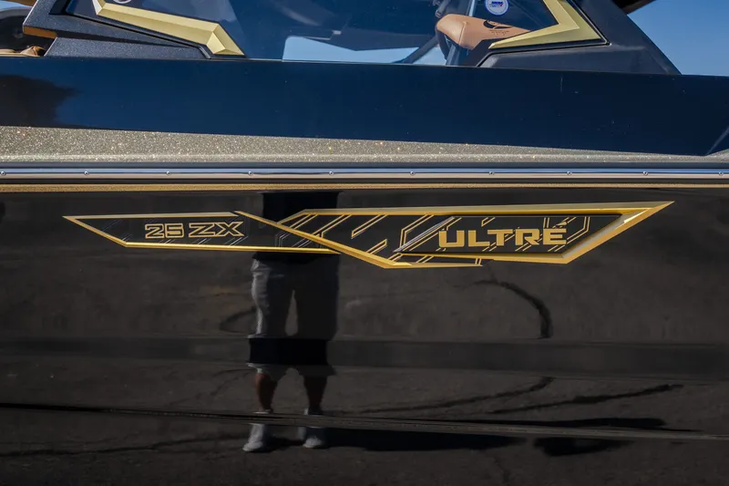 Slide: The Image of 2027 Tigé Ultré 25ZX boat with sleek black and gold detailing. - 24