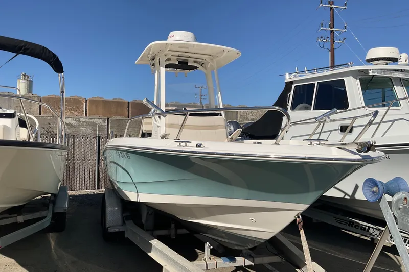 The Image of 2023 Boston Whaler 220 Dauntless boat on trailer, parked outdoors under clear blue sky. - 0