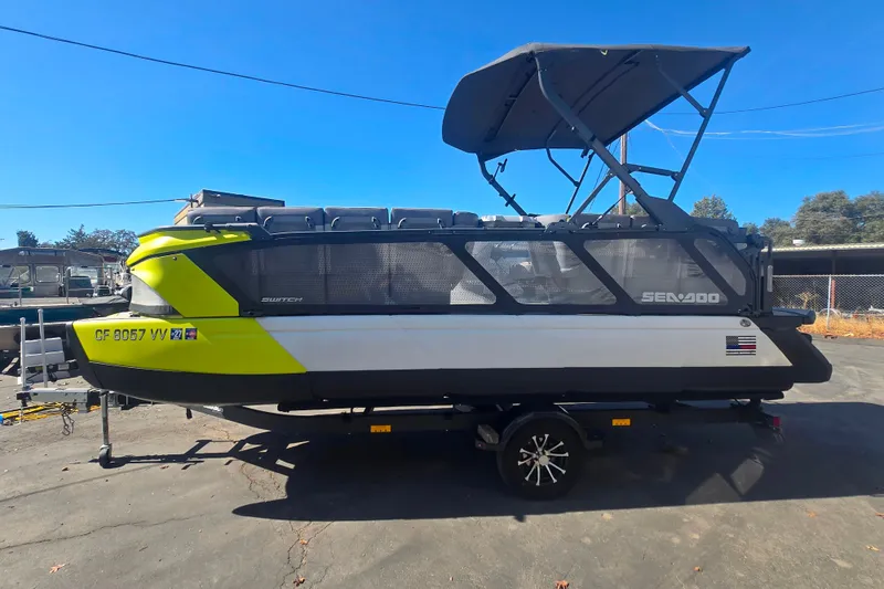 Slide: The Image of 2023 Sea-Doo Switch Cruise 21 pontoon boat with canopy, parked on a trailer. - 1