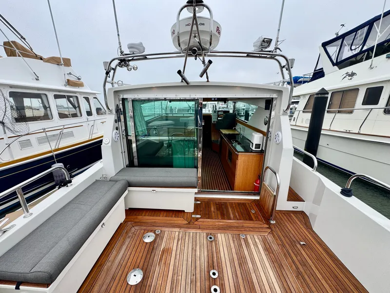 Slide: The Image of The image shows the deck of a 2013 Delta Powerboats 40 Walk Around with wooden flooring and seating area. - 28