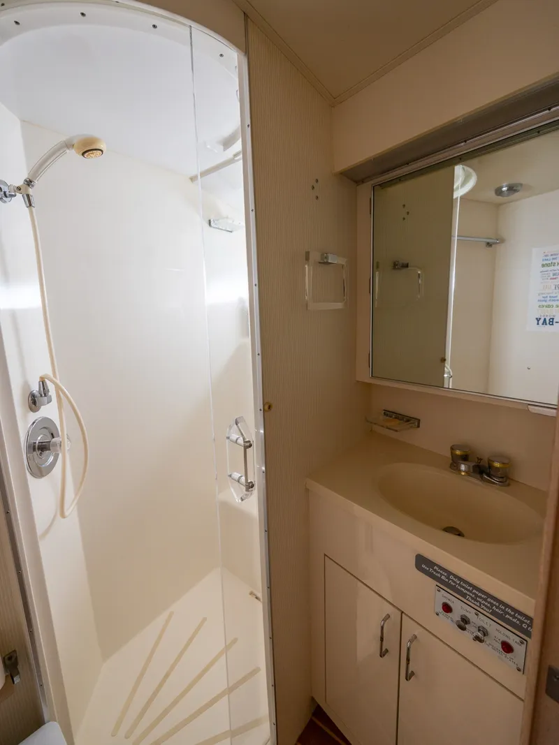 Slide: The Image of The image shows a bathroom with a shower and sink in a 1995 Hatteras 52 Cockpit Motor Yacht. - 47