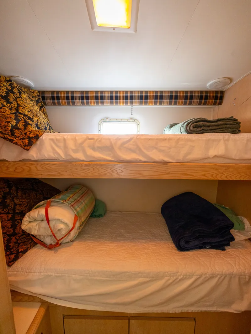 Slide: The Image of Interior with two bunk beds, blankets, and pillows in a cozy room with a small window. - 45