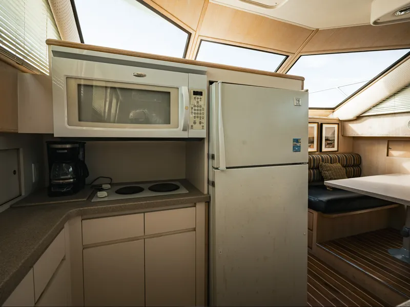 Slide: The Image of The 1995 Hatteras 52 Cockpit Motor Yacht's kitchen features a refrigerator, microwave, and stove. - 36