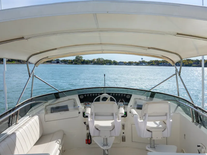 Slide: The Image of The cockpit of a 1995 Hatteras 52 Motor Yacht with two white seats and a steering wheel. - 24