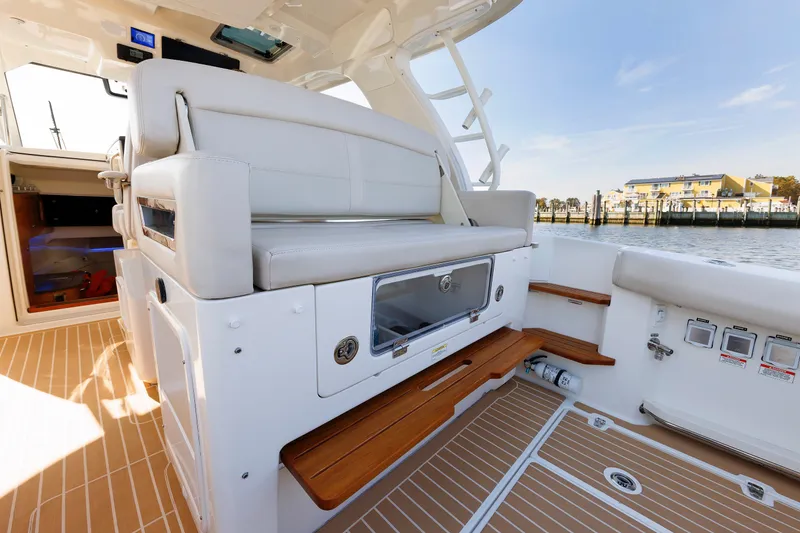 Slide: The Image of 2020 Boston Whaler 380 Realm interior with seating and wooden accents, dockside view. - 45