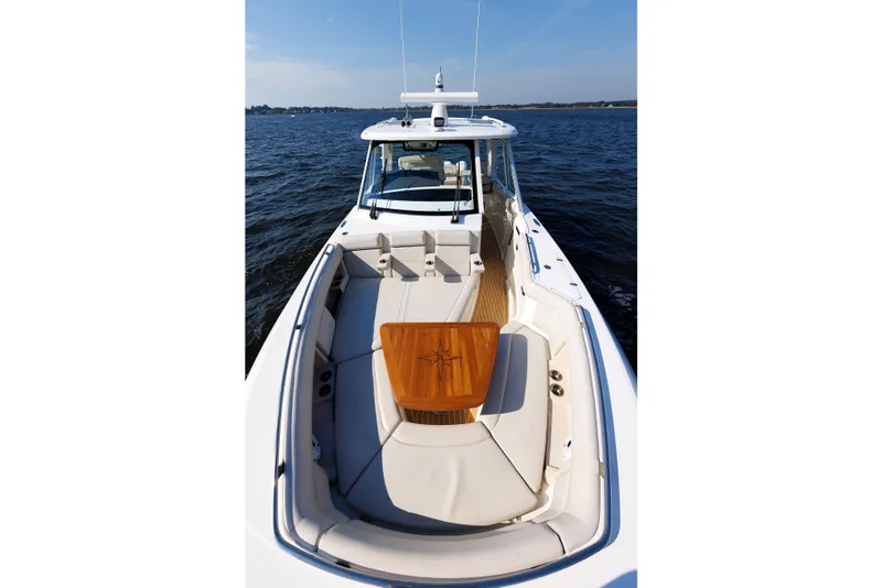 Slide: The Image of 2020 Boston Whaler 380 Realm boat with spacious seating and wooden table on open water. - 63