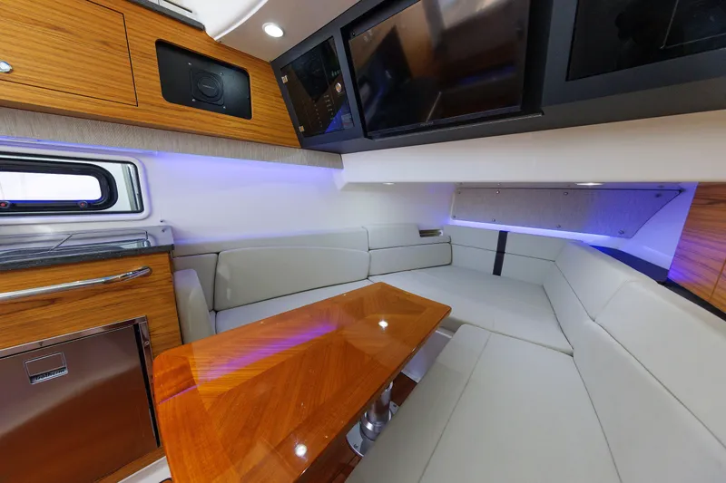 Slide: The Image of 2020 Boston Whaler 380 Realm interior with modern seating, wood accents, and ambient lighting. - 70