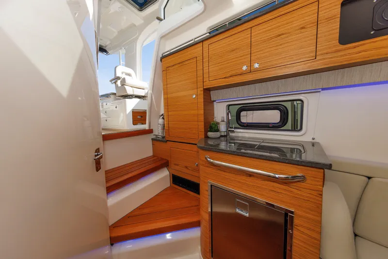 Slide: The Image of Interior of 2020 Boston Whaler 380 Realm, featuring wooden cabinetry and compact kitchenette. - 66