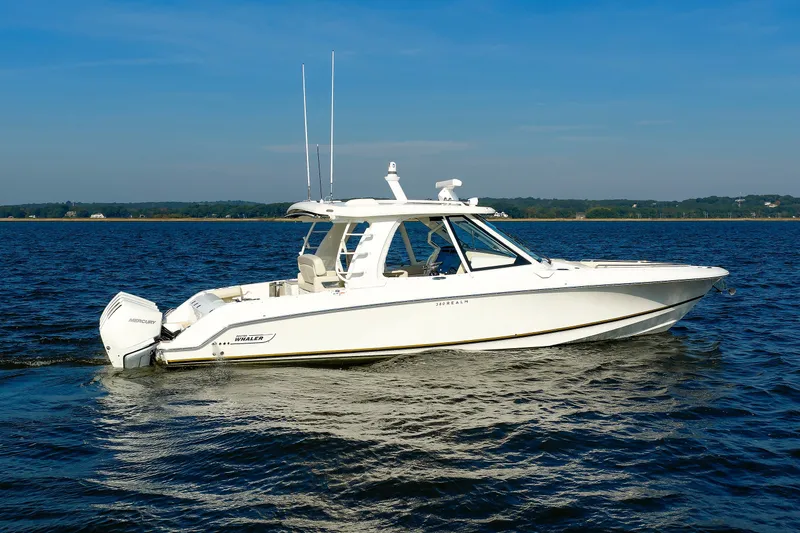 Slide: The Image of 2020 Boston Whaler 380 Realm boat cruising on a calm lake under a clear blue sky. - 11