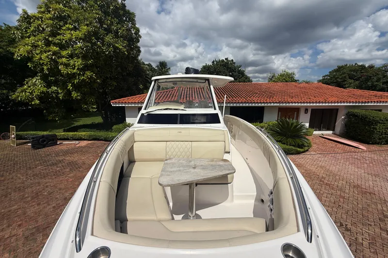 Slide: The Image of 2019 Regal 33 SAV boat with spacious seating and table, parked near a house. - 33