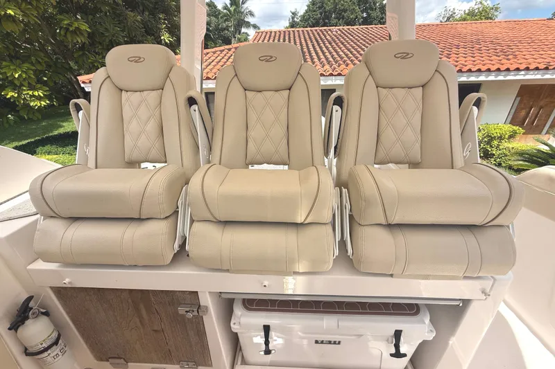 Slide: The Image of Three beige leather seats with quilted pattern on a Regal boat, surrounded by green landscape. - 14