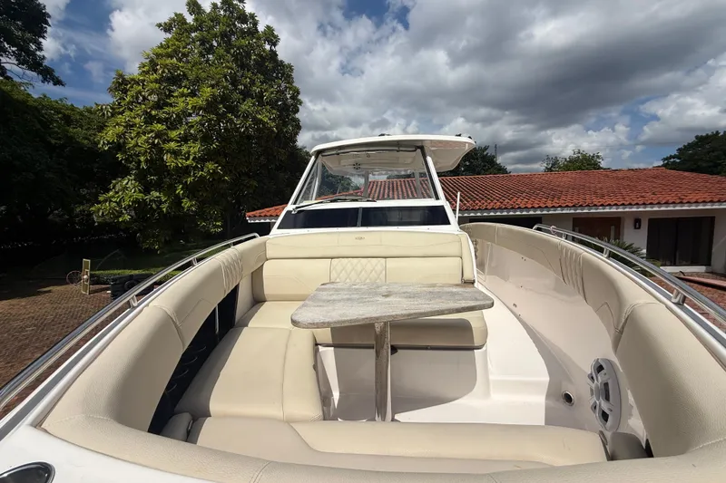 Slide: The Image of 2019 Regal 33 SAV boat with beige seating and table, under a cloudy sky. - 31