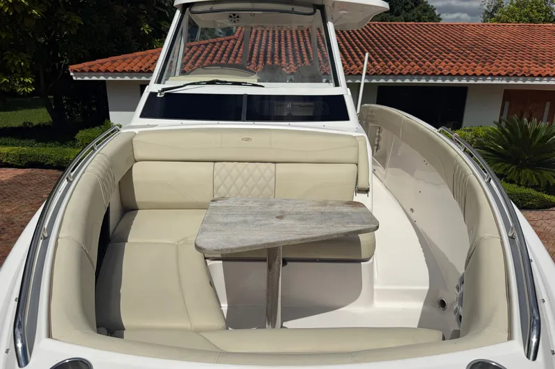 Slide: The Image of 2019 Regal 33 SAV boat with beige seating and wooden table in a sunny setting. - 32