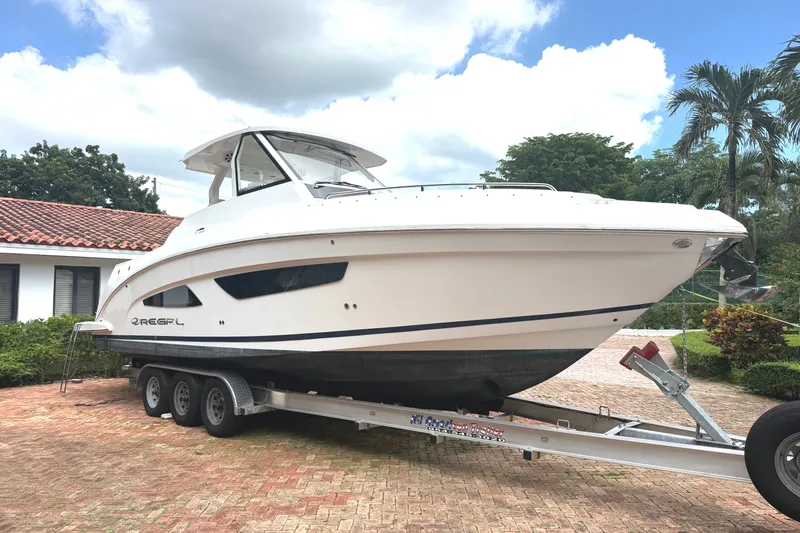 The Image of A white 2019 Regal 33 SAV boat on a trailer in a paved courtyard. - 0