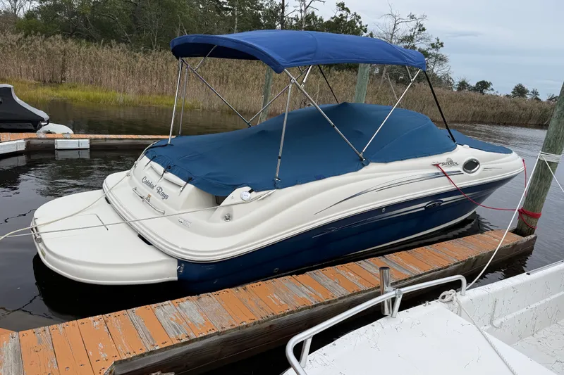Slide: The Image of 2009 Sea Ray 240 Sundeck boat docked with blue cover and canopy. - 2