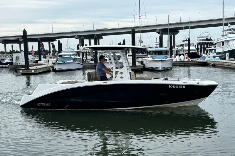 Slide: The Image of 2022 Yamaha Boats 255 FSH Sport E cruising in a marina with bridge backdrop. - 1
