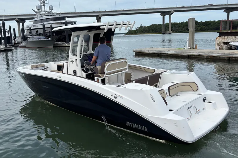 Slide: The Image of 2022 Yamaha Boats 255 FSH Sport E navigating a marina with bridge in background. - 4