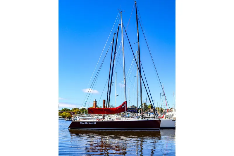 Slide: The Image of 2005 J Boats J/100 sailboat with red sail, docked in a marina under clear blue sky. - 3