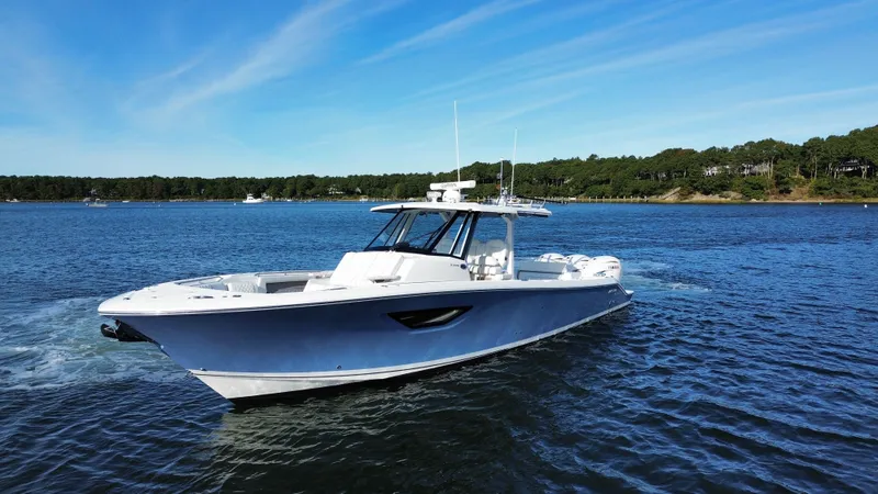 Slide: The Image of 2021 Pursuit S 378 Sport on calm water with wooded shoreline in the background. - 25