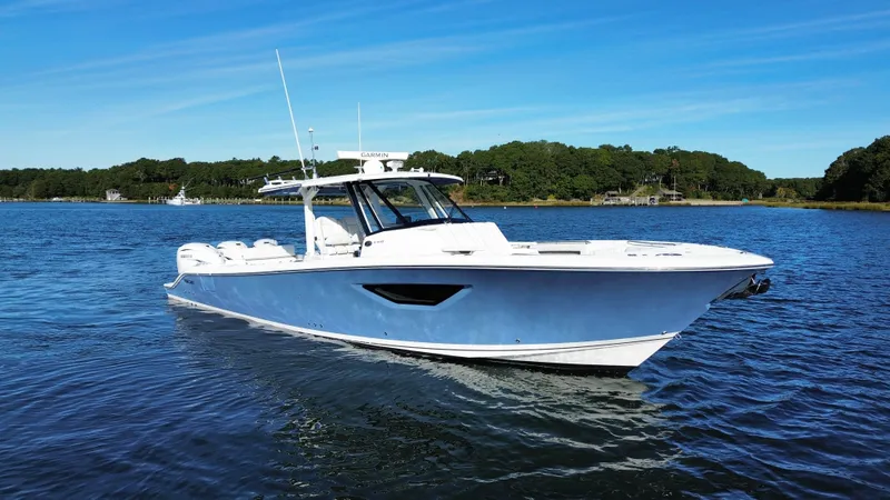 Slide: The Image of A 2021 Pursuit S 378 Sport boat on calm water with a wooded shoreline in the background. - 24