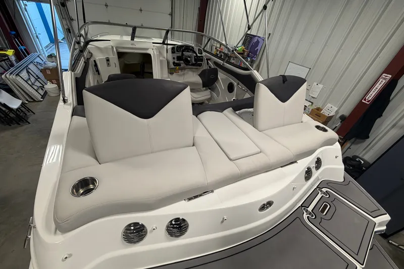 Slide: The Image of 2018 Rinker MTX 22 CC boat interior with cushioned seating and modern design in a storage facility. - 7