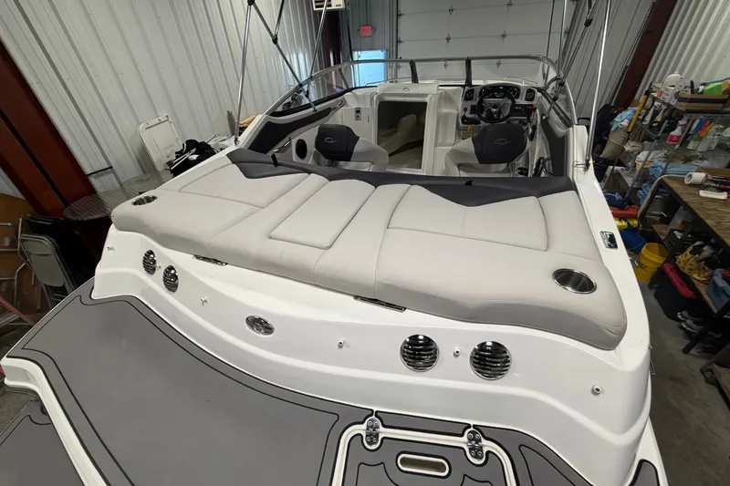 Slide: The Image of 2018 Rinker MTX 22 CC boat interior with cushioned seating and steering console in a garage. - 6