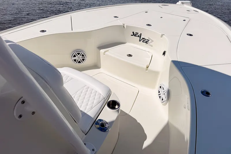 Slide: The Image of 2016 SeaVee 270Z boat interior with white seating and cup holders on calm water. - 24